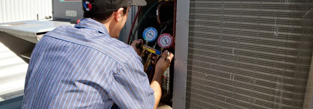 HVAC technician servicing a condenser unit in Wyckoff